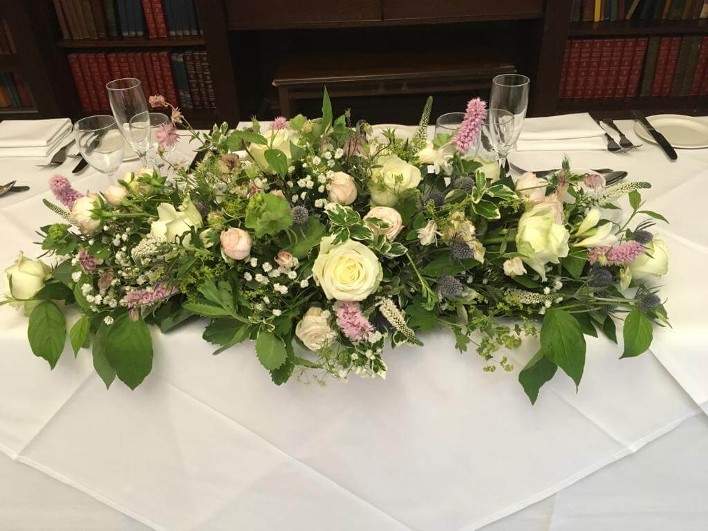 Pink and cream top table wedding centrepiece, with seasonal greenery